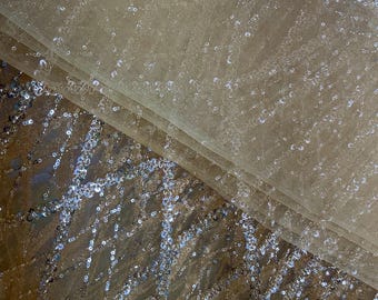 May include: Beige sheer fabric with silver sequins scattered throughout. The fabric is folded in half, revealing a layer of sequins underneath.