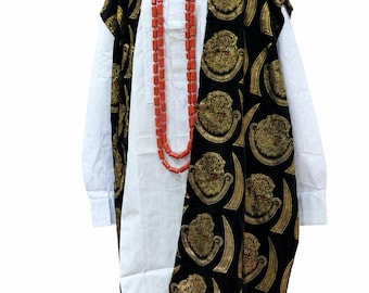 May include: A white long-sleeved shirt worn under a black sleeveless tunic featuring a gold embroidered lion and curved blade pattern. The outfit includes a long necklace of orange cylindrical beads and a small, round, solid red cap.