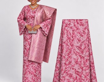 Könnte beinhalten: Ein Set aus mauvefarbenem und magentafarbenem Spitzenstoff, bestehend aus einem langärmeligen Kleid mit gewelltem Saum und einer passenden Kopfbedeckung. Das florale Muster ist mit Metallicfäden durchzogen und schimmert.
