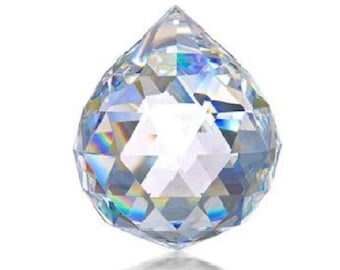 Puede incluir: Una bola de cristal transparente con un diseño facetado. La bola es iridiscente y refleja la luz.