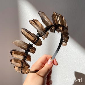 May include: A brown crystal headband with wire wrapped around the crystals. The headband is made of black metal.