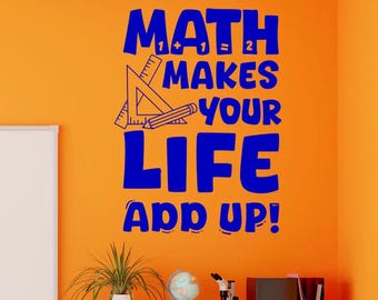 May include: A blue wall decal featuring the text MATH MAKES YOUR LIFE ADD UP! with a graphic of a triangle ruler and a pencil. The decal is applied to a bright orange wall above a white shelving unit in a classroom setting.