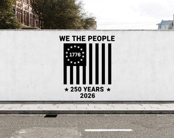 May include: A black graphic design on a white wall featuring the text WE THE PEOPLE above a stylized flag with thirteen stars arranged in a circle around the year 1776, with the text 250 YEARS 2026 positioned below the flag design.