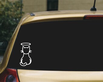 May include: A white vinyl decal sticker applied to a car rear window, featuring a minimalist line art illustration of a cat sitting with its back to the viewer, topped with a simple circular halo floating above the cat's head.