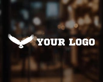 May include: White eagle graphic with outstretched wings and the text "YOUR LOGO" in a bold, sans-serif font. The design is set against a blurred, dark background, suggesting a window or glass surface.