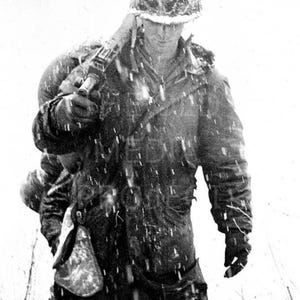 May include: Black and white photograph of a soldier in a winter environment. The soldier is wearing a helmet, heavy coat, and gloves, carrying a rifle and a pack. Snow is falling, creating a stark, cold scene.