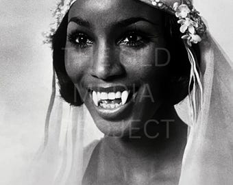 May include: Black and white portrait of a woman with long eyelashes, wearing a floral headpiece and a sheer veil. She is smiling, revealing elongated fangs, a classic vampire look.