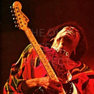 May include: A vintage photograph of a musician playing a Fender Stratocaster guitar. The guitar has a white body and a maple neck. The musician is wearing a colorful patterned shirt and a choker. The background is dark.