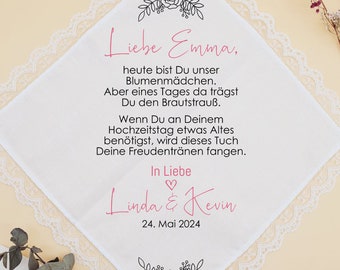 May include: White lace handkerchief with a black floral border and text that reads "Liebe Emma, heute bist Du unser Blumenmädchen. Aber eines Tages da trägst Du den Brautstrauß. Wenn Du an Deinem Hochzeitstag etwas Altes benötigst, wird dieses Tuch Deine Freudentränen fangen. In Liebe Linda & Kevin 24. Mai 2024"