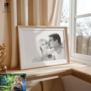 May include: A framed black and white portrait of a couple kissing, with a wooden frame. The image is displayed on a wooden surface near a window with beige curtains. The text "CREATIVE GIFTS" and "DRAWN BY PEN" is visible in the upper left corner.