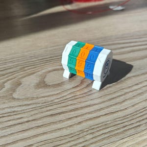 Op de afbeelding: Een witte, driezijdige, draaibare getallenkubus met groene, oranje en blauwe zijden. Elke zijde heeft de getallen 0-9 erop gedrukt.