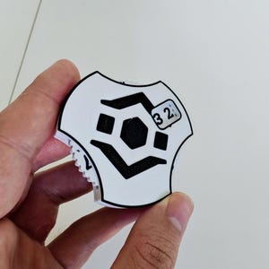 Könnte beinhalten: Weißer Schaumstoffaufkleber mit einem schwarzen geometrischen Design und der Nummer "32" darauf gedruckt.