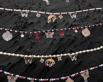 May include: Five strands of beaded necklaces with various charms, including butterflies, lanterns, umbrellas, and flowers. The necklaces are layered on a dark background.