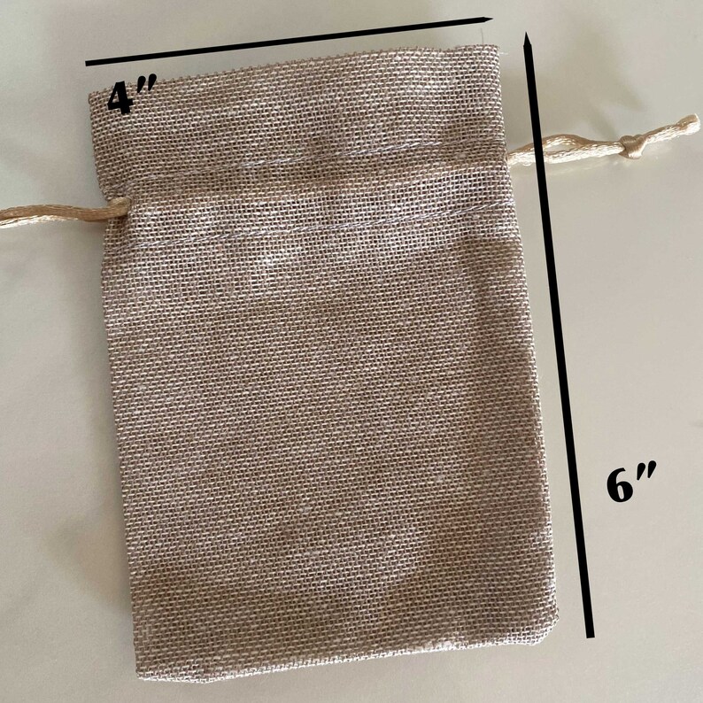 Op de afbeelding: Een klein, beige jute trekkoordtasje met een afmeting van 10 cm bij 15 cm. De tas heeft een natuurlijke, rustieke uitstraling en is perfect voor kleine cadeautjes of attenties.