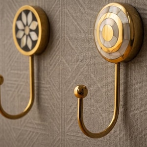 Peut inclure: Ensemble de trois mugs en céramique crème tachetée. Chaque mug présente un motif peint à la main : une feuille bleue et verte, une fleur jaune et une baie rouge. Les mugs ont une forme simple et arrondie.