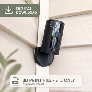 May include: A black cylindrical security camera mount featuring the word ring on the front. The digital download includes a 3D print file in STL format. The mount is designed to attach to a corner, with a flat base and a vertical arm for the camera.
