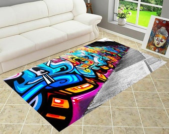 Op de afbeelding: Een kleurrijk, abstract tapijt met een graffiti-ontwerp. Het tapijt heeft een verscheidenheid aan kleuren, waaronder blauw, geel, roze en zwart. Het ontwerp doet denken aan straatkunst en heeft een verscheidenheid aan vormen en patronen.