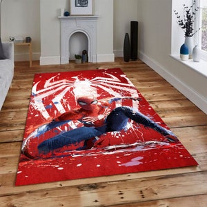 Puede incluir: Alfombra roja y azul de Spider-Man con salpicaduras de pintura blanca y un dise&ntilde;o de telara&ntilde;a blanca. El superh&eacute;roe est&aacute; en una pose din&aacute;mica con los brazos extendidos.