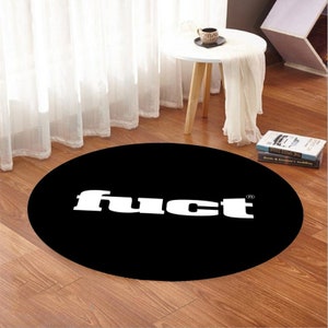 May include: A black and white round rug with the word "fuCt" printed in white letters on a black background.