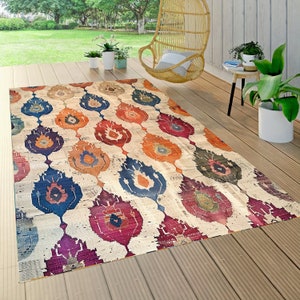 May include: A colourful outdoor rug with a geometric pattern of teardrop shapes in shades of blue, red, orange, and purple on a cream background.