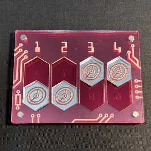 May include: A magenta circuit board with four hexagonal insets, each with a silver and copper design. Numbers 1 to 4 are printed above the insets. The board has a circuit design around the edges. The measurements are in centimetres.