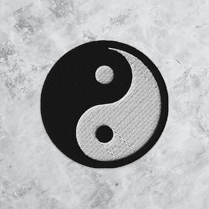 May include: A black and white yin yang symbol embroidered on a fabric patch. The yin yang symbol is a circular design with two halves, one black and one white, each containing a smaller circle of the opposite color.