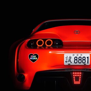 May include: A red sports car with a black heart sticker that says "Stay Weird" and a license plate that says "台北市 8881".