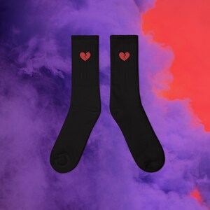 Könnte beinhalten: Ein Paar schwarze Socken mit einem roten gebrochenen Herzdesign auf jeder Socke.