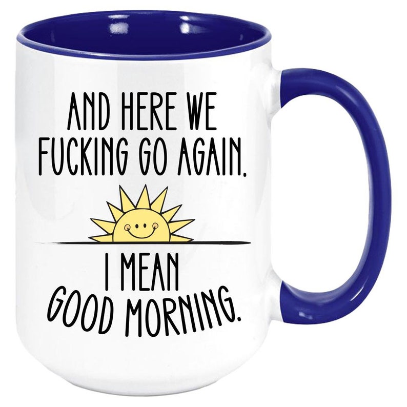 Pode incluir: Caneca de caf&eacute; branca com borda e al&ccedil;a azuis. A caneca tem um ditado engra&ccedil;ado que diz "And here we fucking go again. I mean good morning."