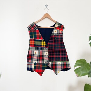 May include: A patchwork vest with a variety of plaid patterns in red, green, blue, and yellow. The vest has a V-neck and is sleeveless.