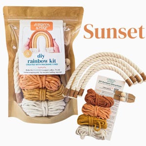May include: DIY macrame rainbow kit in sunset colors. The kit includes three different colors of macrame cord, a wooden dowel, and instructions. The kit is packaged in a clear plastic bag with a brown paper label.