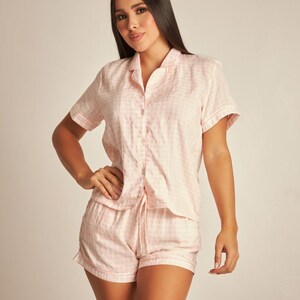 May include: A pink and white gingham pyjama set with a short-sleeved button-up top and matching shorts.