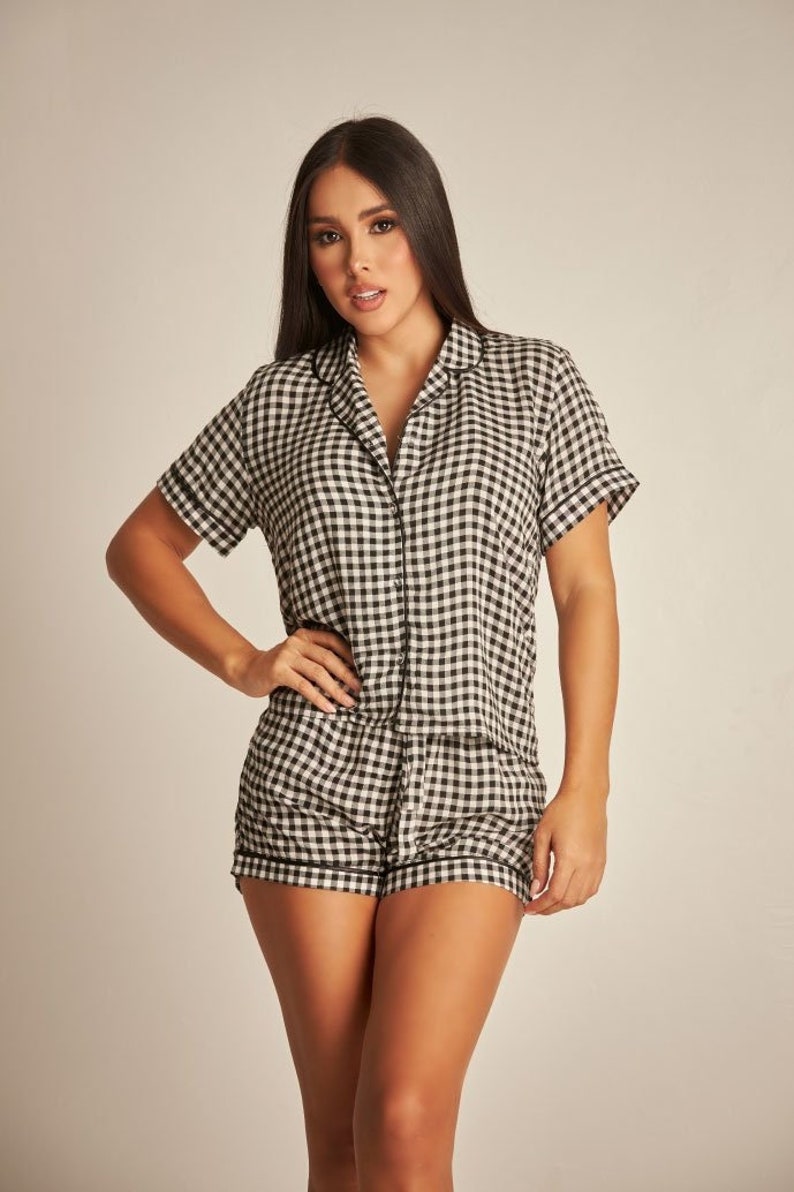 May include: A black and white gingham pyjama set with a short-sleeved button-up top and matching shorts.
