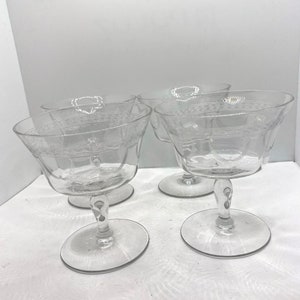 May include: Set of four clear glass champagne coupes with a decorative etched pattern.