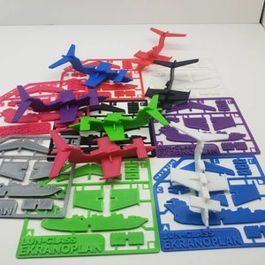 May include: A collection of colorful, unassembled model airplanes in various colors, including red, blue, green, purple, and gray. Each model is on a plastic sprue with the text "LUN-CLASS EKRANOPLAN".