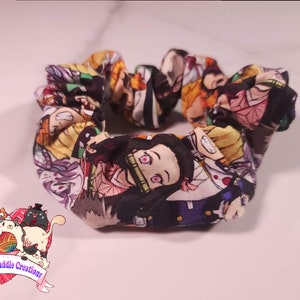 May include: A black and white scrunchie with a colorful anime print featuring characters from the show "Demon Slayer".
