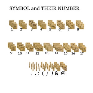 May include: A set of 17 gold-toned metal stamps with various symbols and punctuation marks. The stamps are arranged in rows and numbered 1 through 17. The symbols include a heart, a star, an infinity symbol, a butterfly, an eye, a clover, a flower, and a sun. The punctuation marks include a period, a comma, a colon, a parenthesis, a slash, an ampersand, and an at symbol.