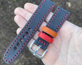 May include: Two black leather watch straps with red stitching. One strap has a silver buckle and the other has three layers of orange, red, and brown leather.