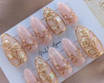 Rosa pintada a mano, uñas postizas rosas con perlas de hilo, detalles dorados y de concha
