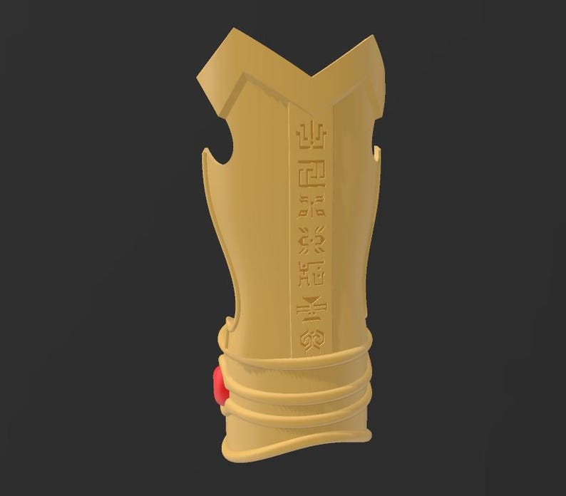May include: A golden-colored arm guard with engraved symbols and a red gem. The arm guard has a curved shape with a series of horizontal lines near the bottom. The background is a solid dark gray.