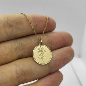 May include: A gold necklace with a round pendant featuring a delicate engraved floral design.