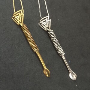 May include: Two necklaces with a spoon-shaped pendant. The pendant is a silver-colored triangle with a braided design. One necklace has a gold chain and the other has a silver chain.