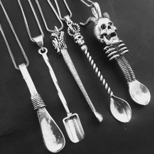 May include: Five silver spoon pendants on chains. The spoons are different shapes and styles, including a skull, a dragon, and a shovel.