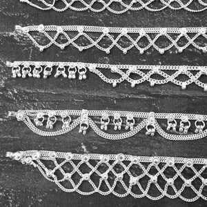 Pode incluir: V&aacute;rias tornozeleiras de prata com v&aacute;rios designs s&atilde;o exibidas. As tornozeleiras apresentam padr&otilde;es intrincados, incluindo correntes, contas e pingentes decorativos. A joia &eacute; feita de um material met&aacute;lico brilhante, e os designs variam.