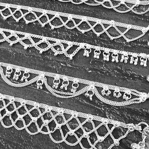 Pode incluir: Close-up de v&aacute;rias tornozeleiras prateadas com designs intrincados. As tornozeleiras apresentam correntes delicadas, detalhes de contas e pingentes pendurados. Os designs incluem padr&otilde;es geom&eacute;tricos e bordas onduladas.