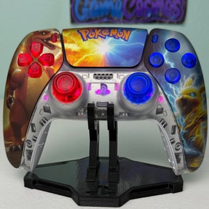 Puede incluir: Un mando PlayStation 5 DualSense blanco con un diseño personalizado de Pokemon que presenta a Pikachu y Charizard. El mando tiene botones iluminados rojos y azules y se muestra en un soporte negro.