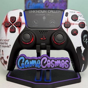 May include: A custom black and white game controller featuring a Ghostface mask graphic, red sound wave patterns, and the text "UNKNOWN CALLER" and "What's your favourite scary movie?" on the faceplate, with red accents on the buttons and joysticks.