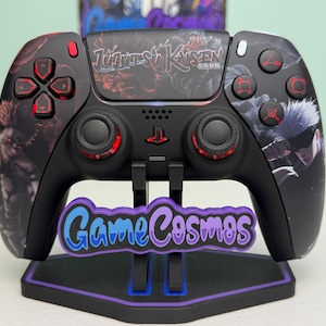 Op de afbeelding: Zwarte PlayStation 5-controller met een Jujutsu Kaisen-ontwerp. De controller heeft rode accenten op de knoppen en joysticks. Het wordt weergegeven op een standaard met de tekst "Game Cosmos" in blauw en paars.
