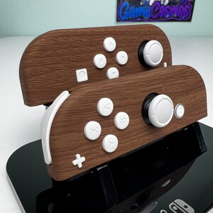 May include: Two wooden Nintendo Switch Joy-Con controllers with white buttons and a black stand. The controllers have a wood grain pattern.