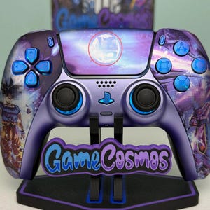 May include: A purple wireless video game controller featuring a custom graphic print of anime characters, blue buttons, and a central touchpad with a circular symbol. The controller is displayed on a black stand with a GameCosmos logo plate.